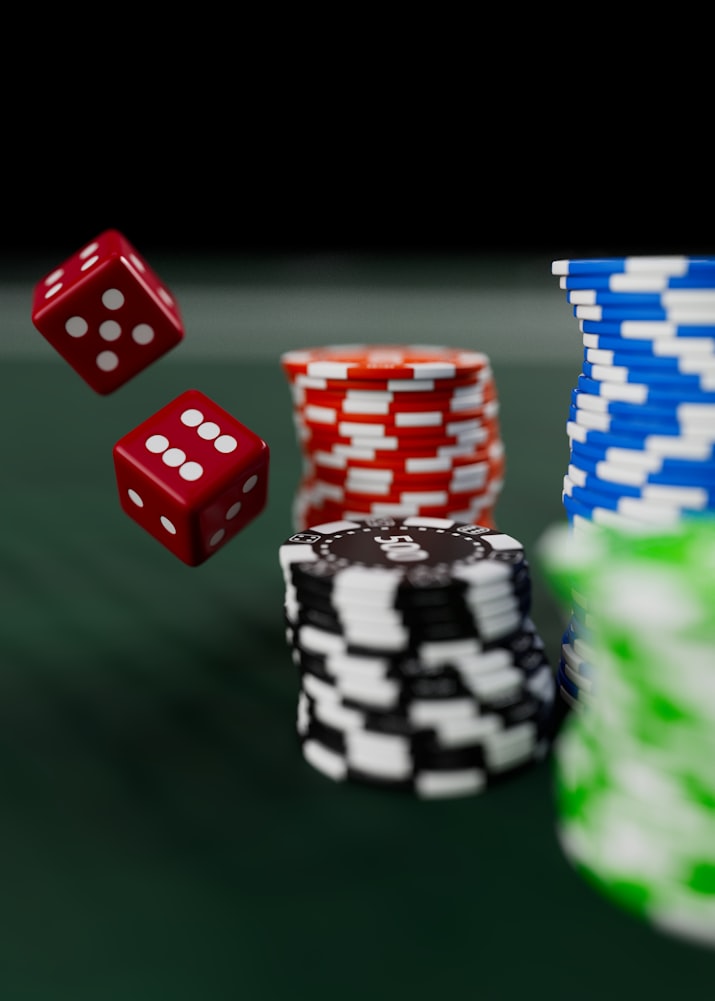 Red and white dice rolling near stacks of colored poker chips on a green table