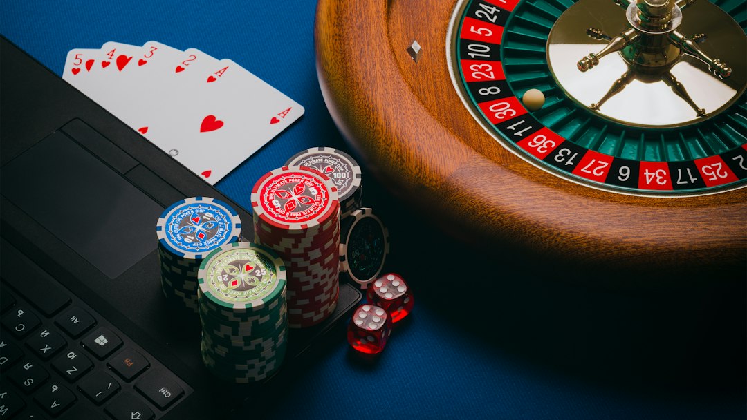 Close-up of a roulette wheel, poker cards, and casino chips on a blue table.